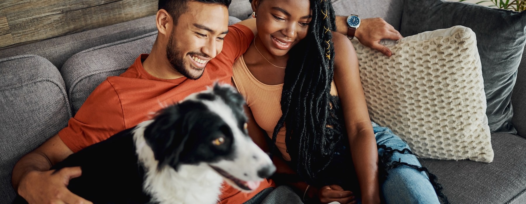 A couple sitting on a couch with their dog