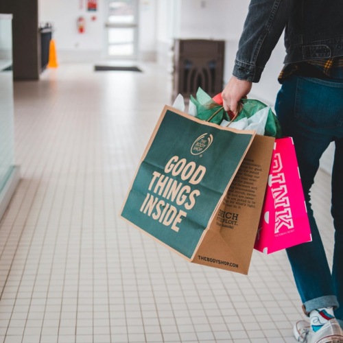 a man walking in a mall with shopping bags and a camera