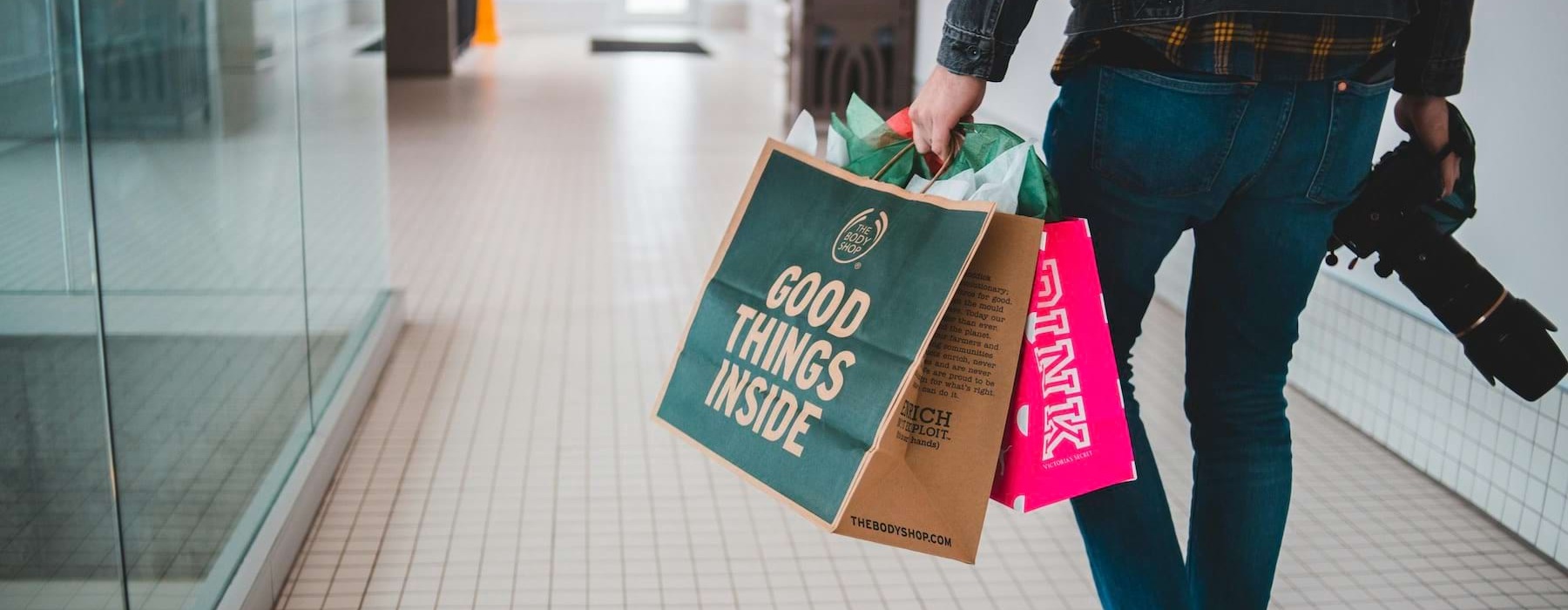 a man walking in a mall with shopping bags and a camera